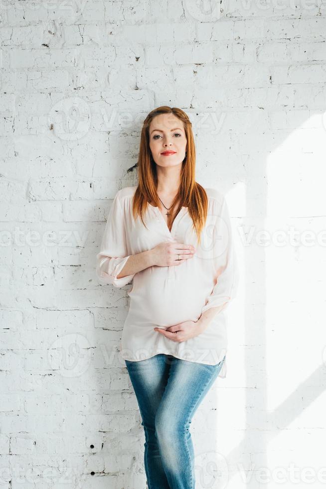 fille enceinte rousse dans un chemisier léger et un jean bleu photo