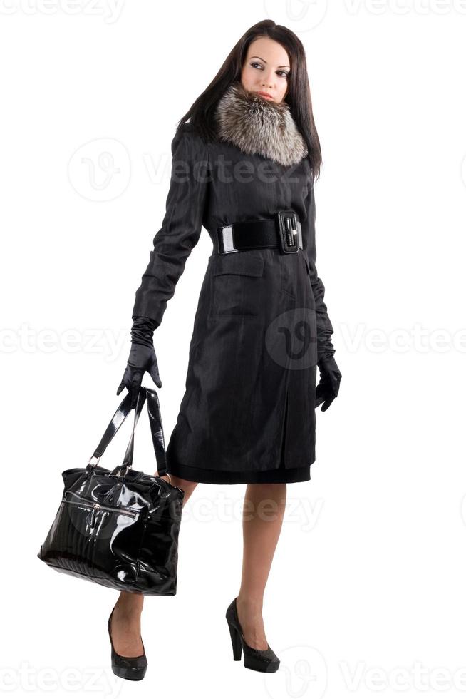 la jeune femme en manteau noir avec un sac. isolé sur blanc photo