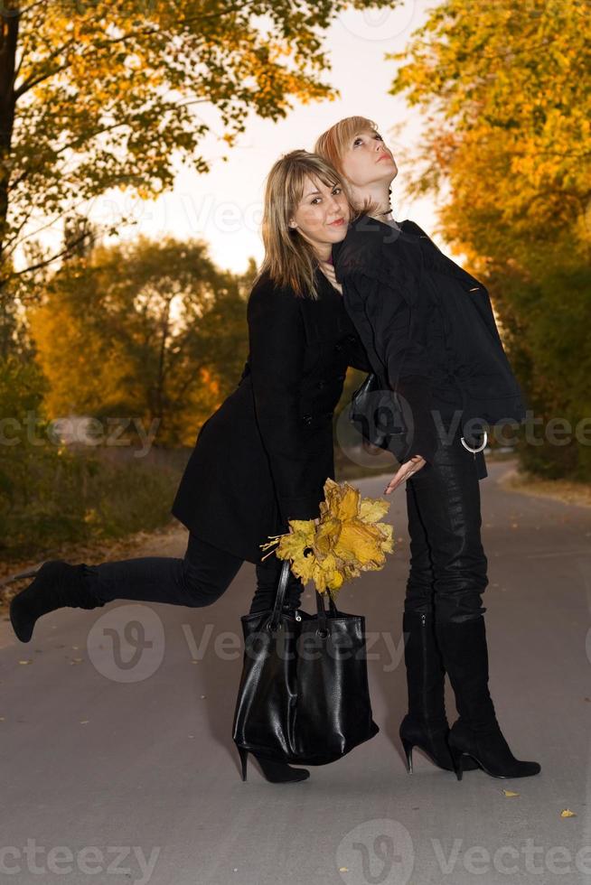 deux jeunes blondes beauté avec des feuilles d'automne sur une route photo