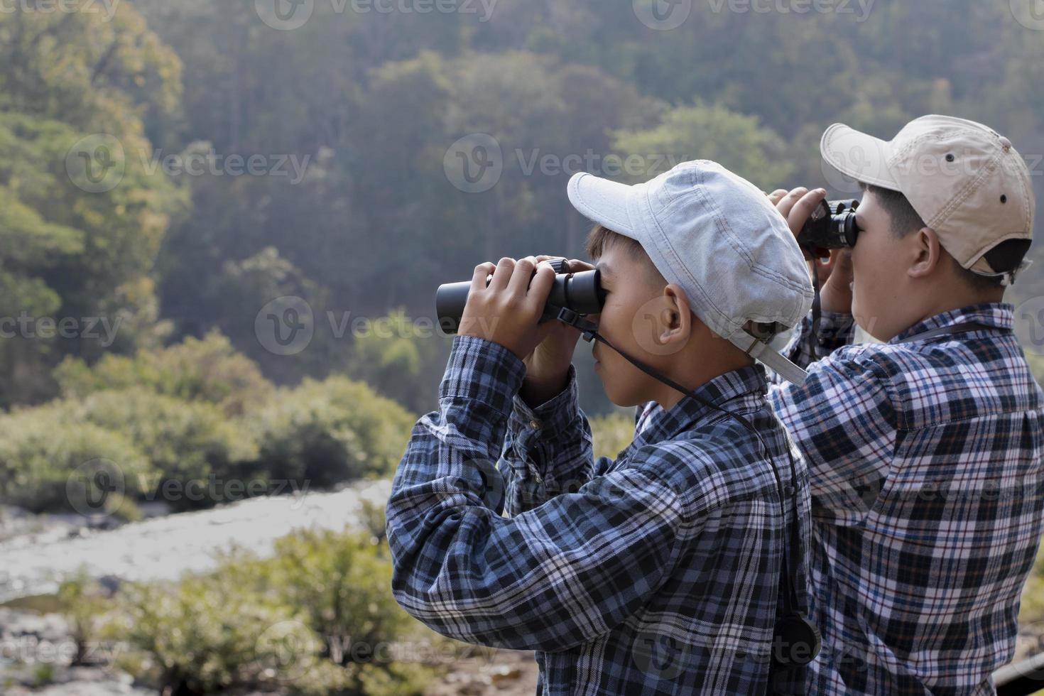 les garçons asiatiques utilisent des jumelles pour observer les oiseaux et les poissons dans le parc national local pendant le camp d'été, idée pour apprendre les créatures et les animaux sauvages et les insectes en dehors de la salle de classe. photo