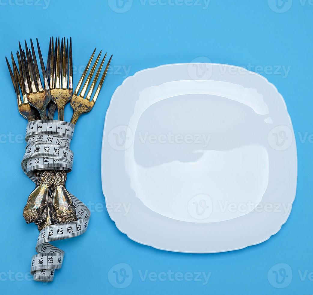 assiette carrée blanche vide et fourchettes enveloppées dans un ruban à mesurer photo