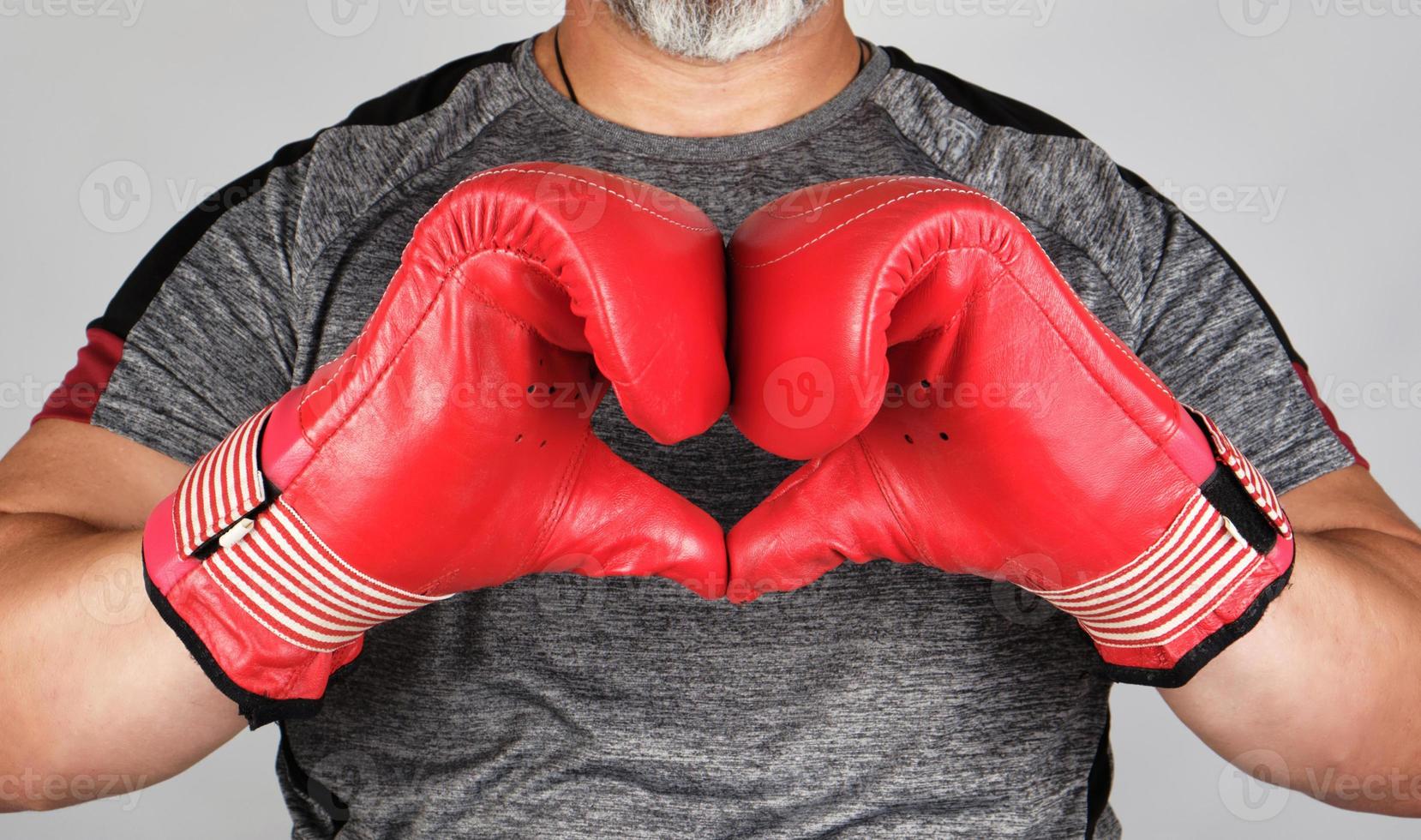 athlète en gants de cuir de boxe rouge montre les mains avec un symbole de coeur photo