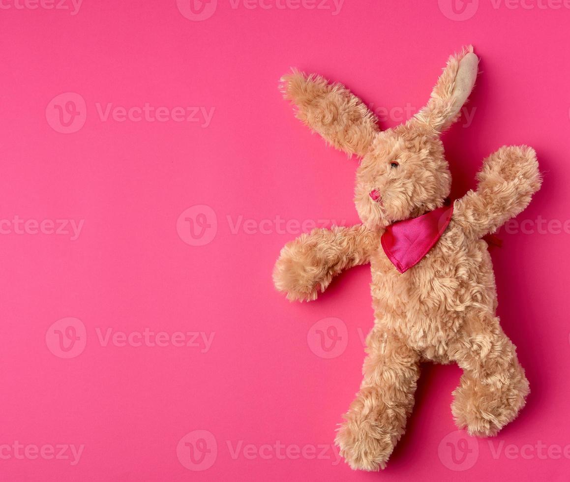 Le lièvre en peluche marron se trouve sur un fond rose photo