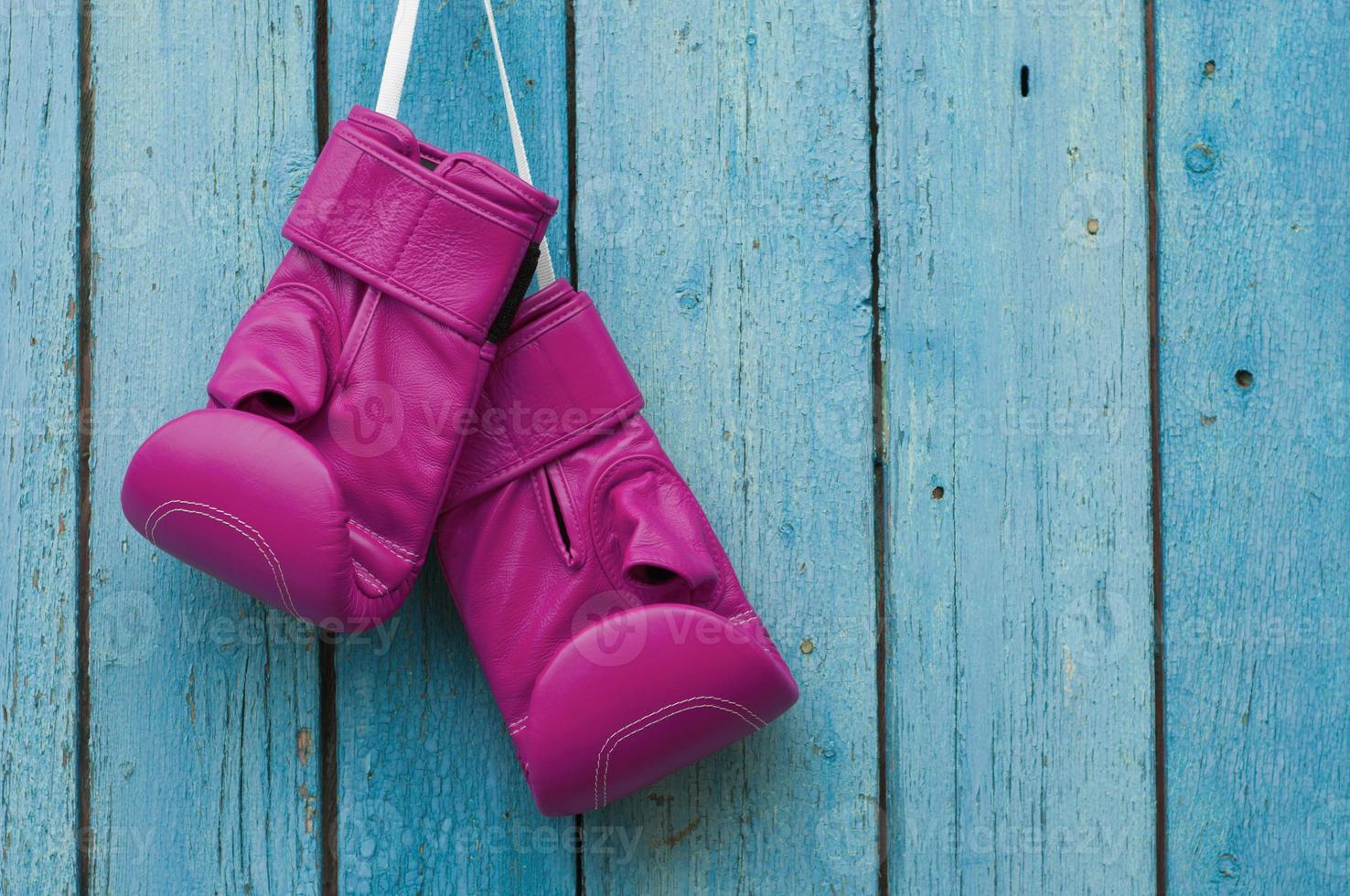 Gants de boxe rose sur fond de bois fissuré bleu photo