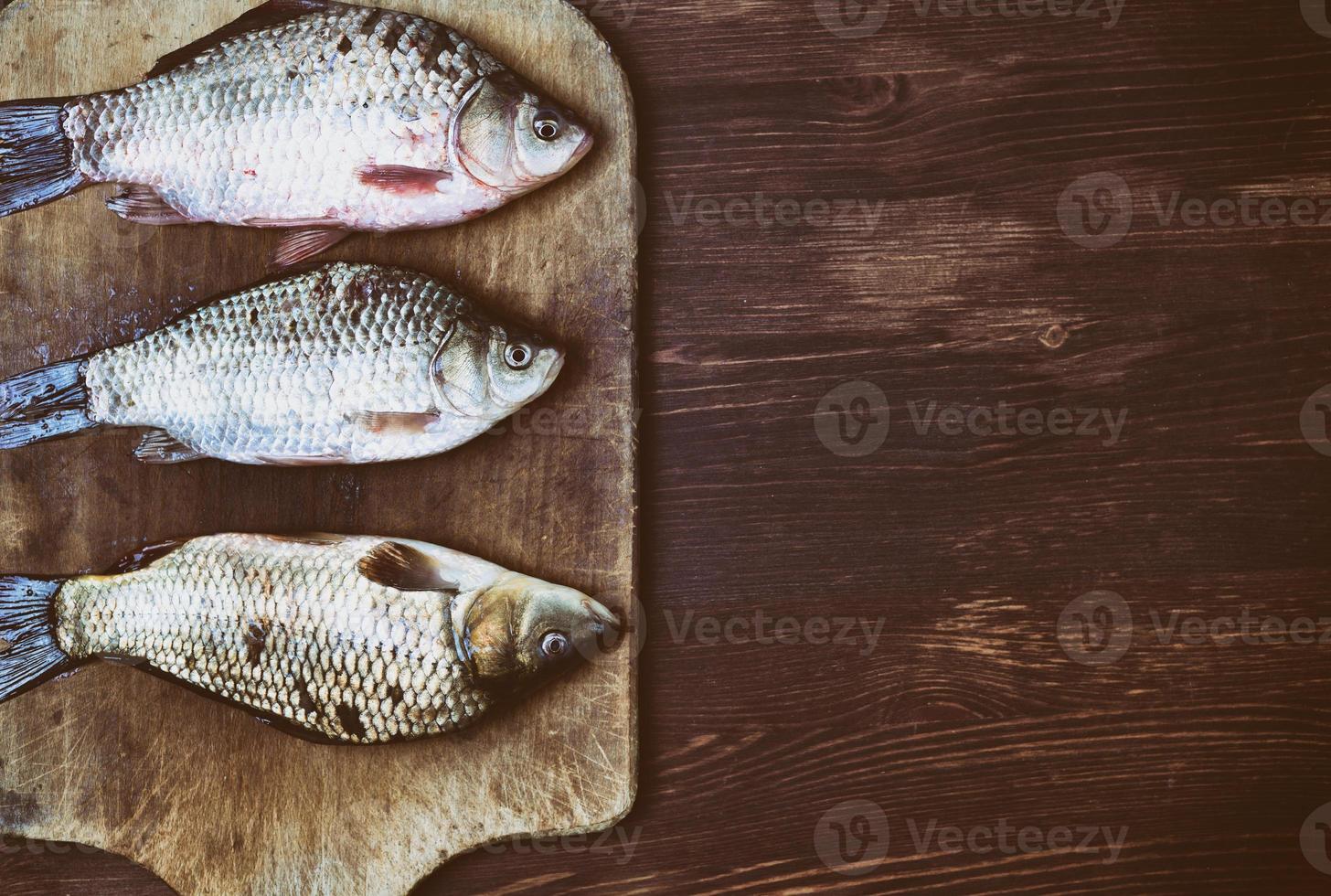 poisson carpe dans les écailles sur la planche à découper de la cuisine photo