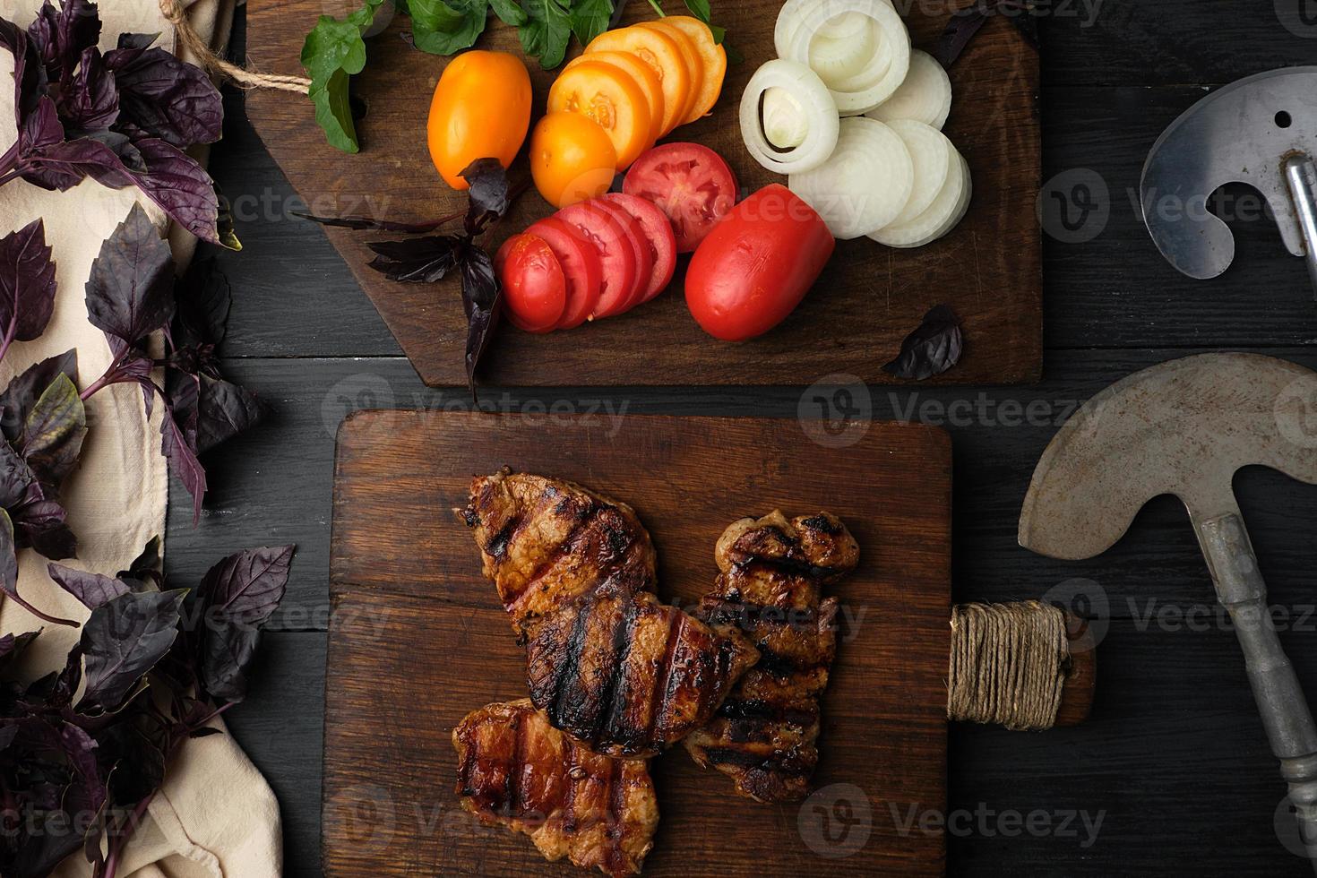 morceaux de viande de porc grillés, à côté d'une planche avec des légumes frais hachés photo