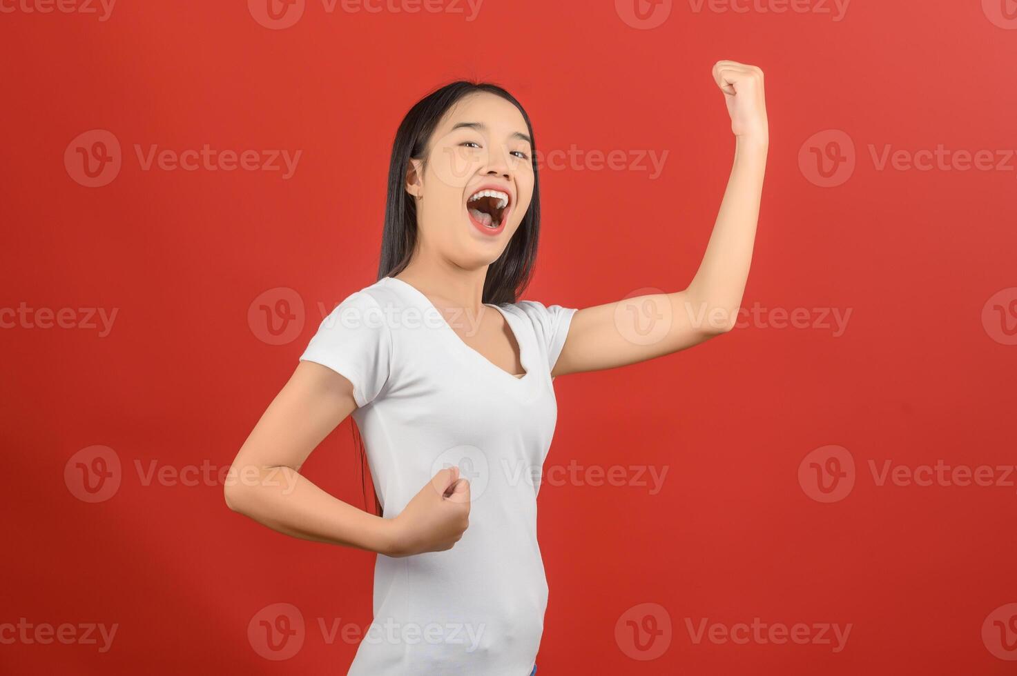 portrait de jeune femme asiatique montrant le geste du gagnant sur fond rouge isolé photo