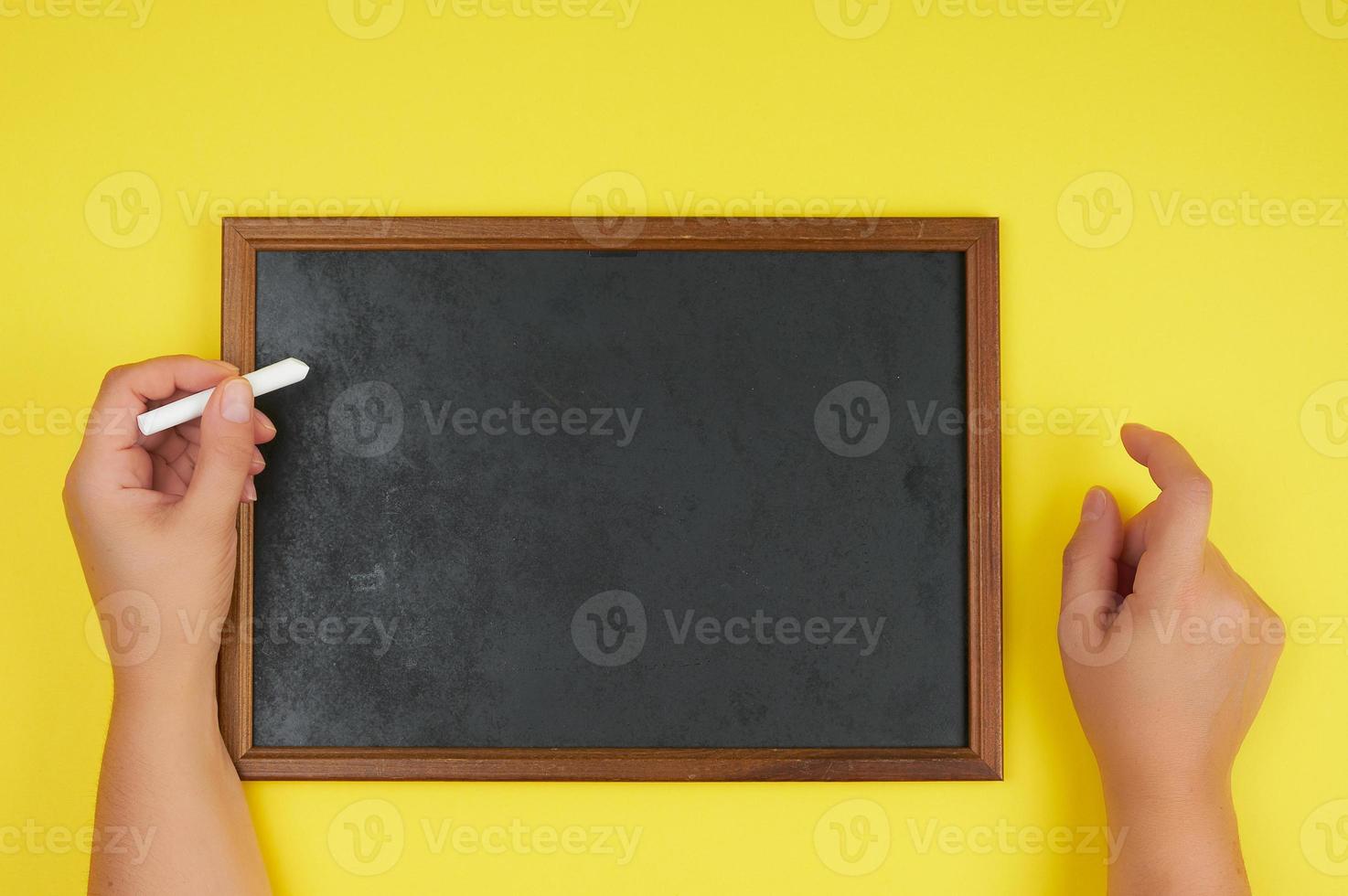 cadre de craie noire et deux mains féminines avec un morceau de craie blanche photo