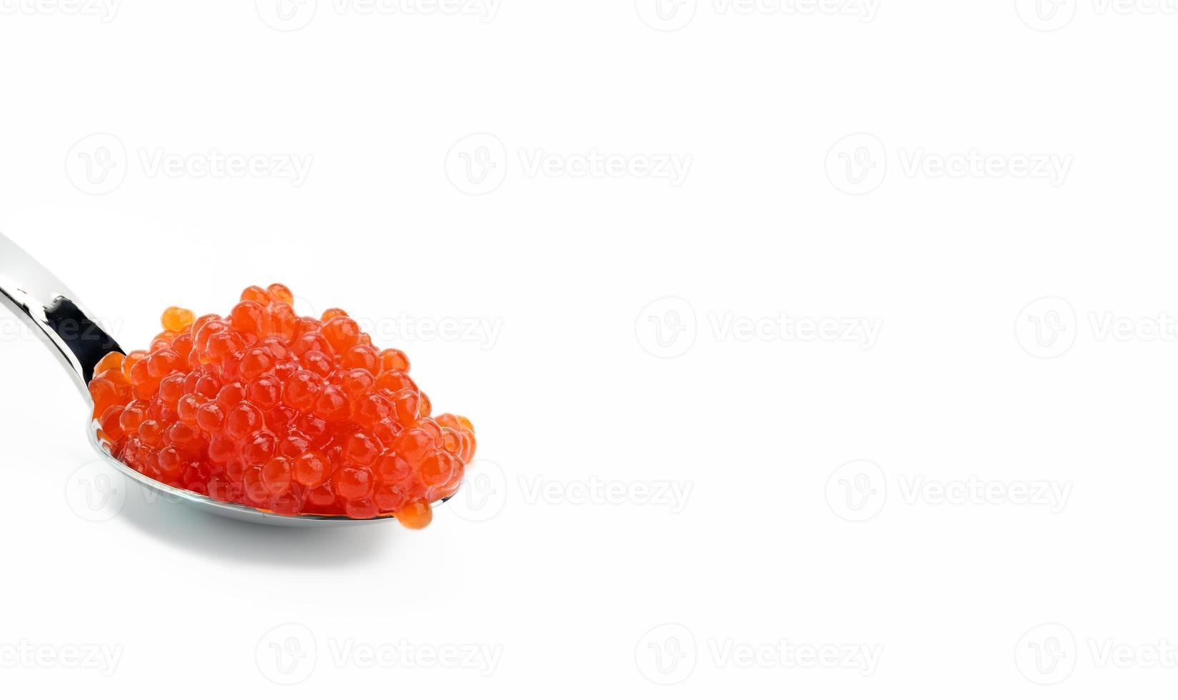 Caviar de saumon kéta rouge à grain frais en cuillère métallique, fond blanc photo