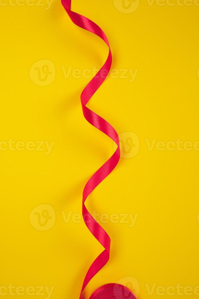 ruban de soie rouge torsadé, fond jaune photo