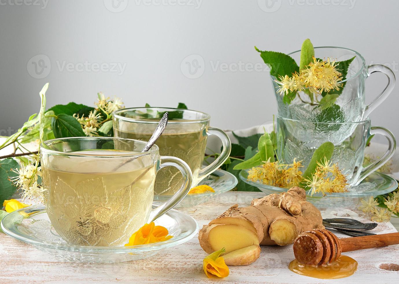 tasse transparente avec du thé au gingembre et au tilleul sur une planche en bois blanche photo