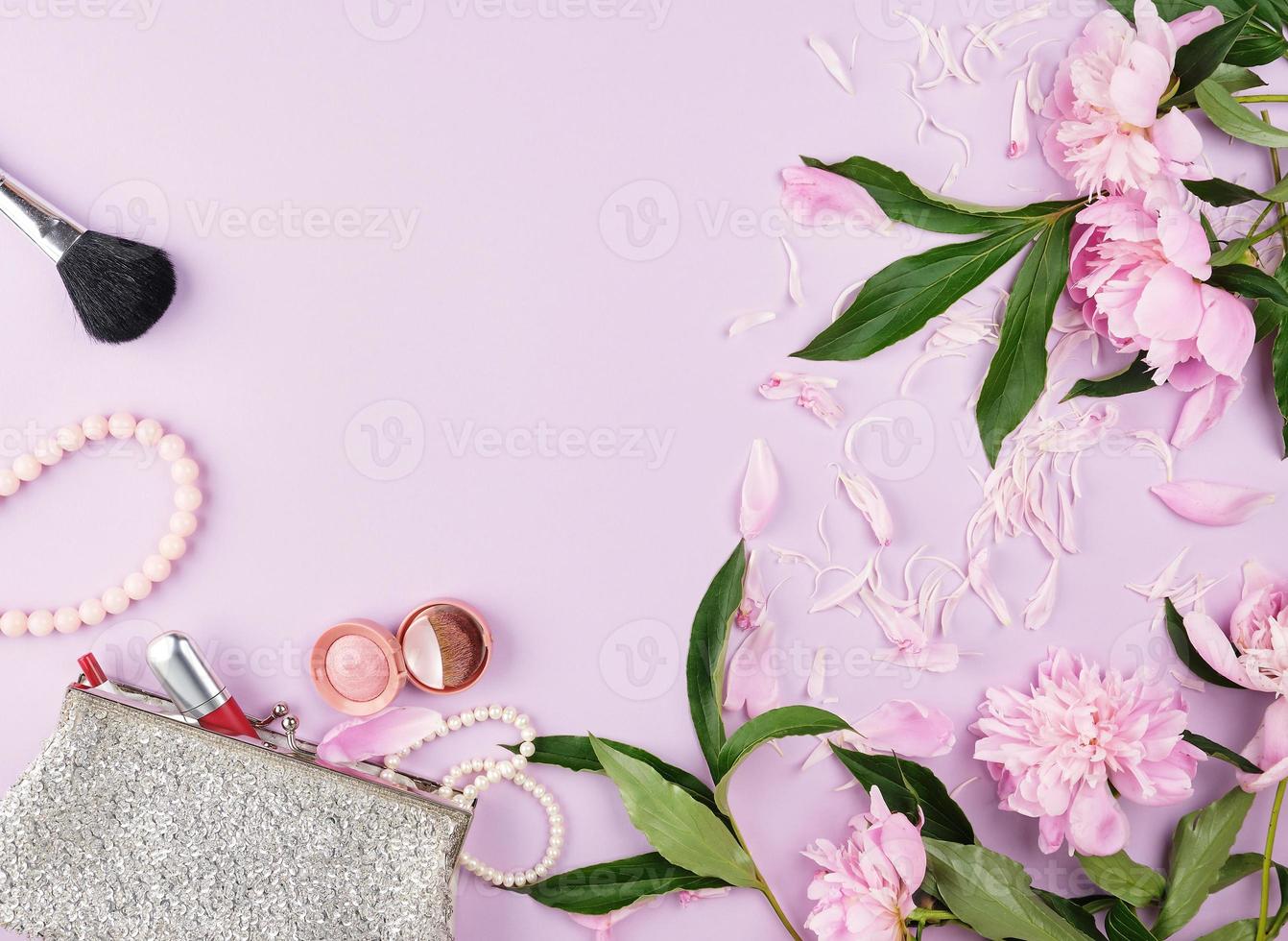 sac cosmétique féminin ouvert en argent avec rouge à lèvres, ombres lumineuses et bracelets en perles photo