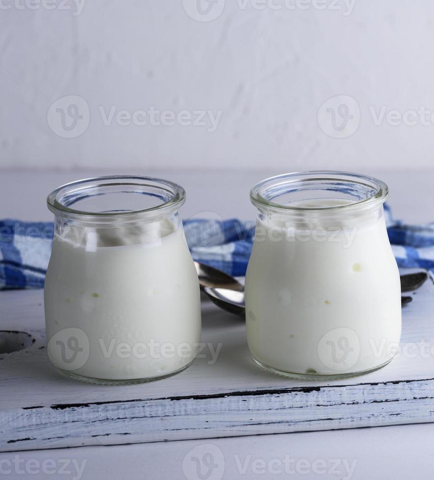 Yaourt fait maison dans un bocal en verre sur une planche de bois blanc photo