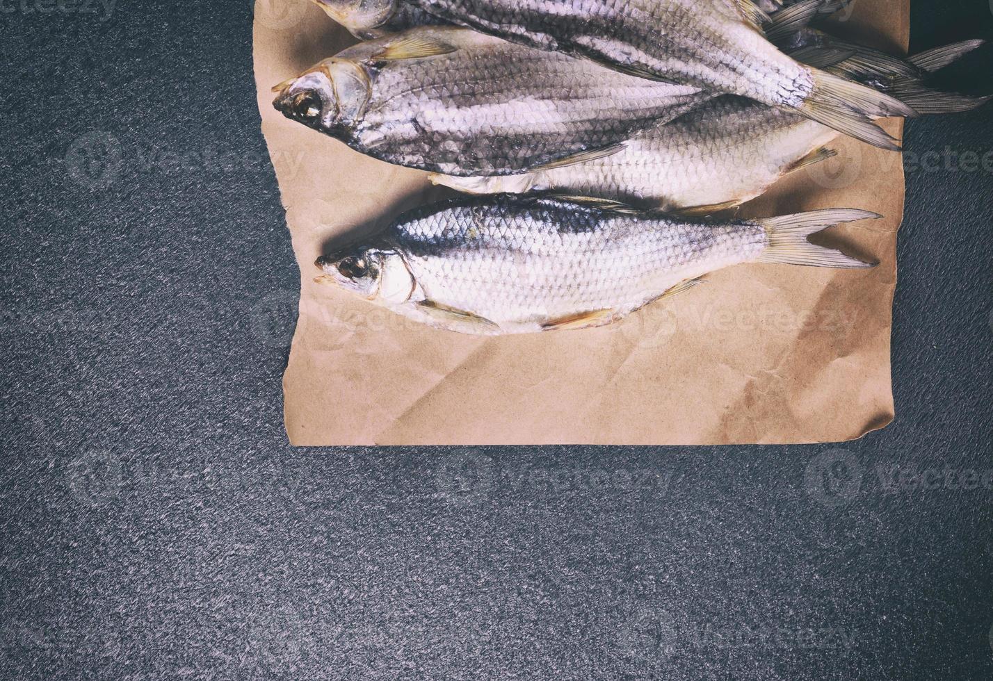 poisson séché entier dans les écailles de gardon allongé sur du papier brun photo