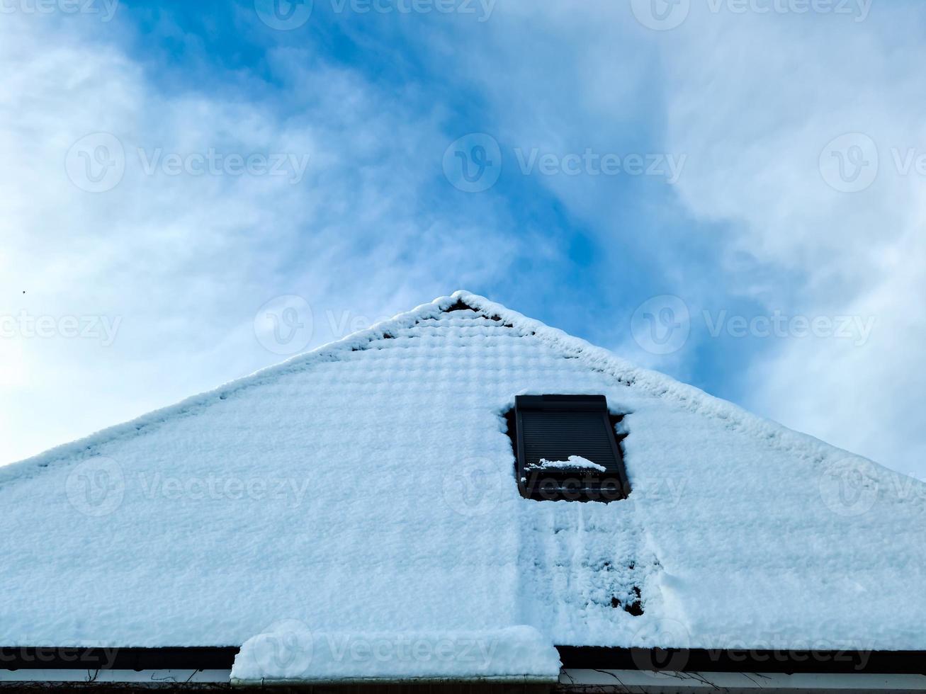 fenêtre de toit ouverte de style velux avec des tuiles noires couvertes de neige blanche photo
