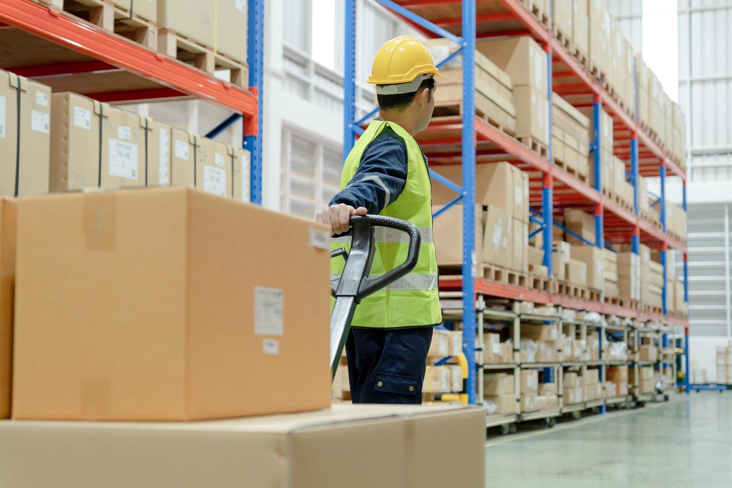 le travailleur de l'entrepôt tire le transpalette après avoir inspecté les marchandises en stock et vérifié le produit en stock. transport logistique expédition et livraison aux clients. inspection, entrepôt, stockage, usine photo