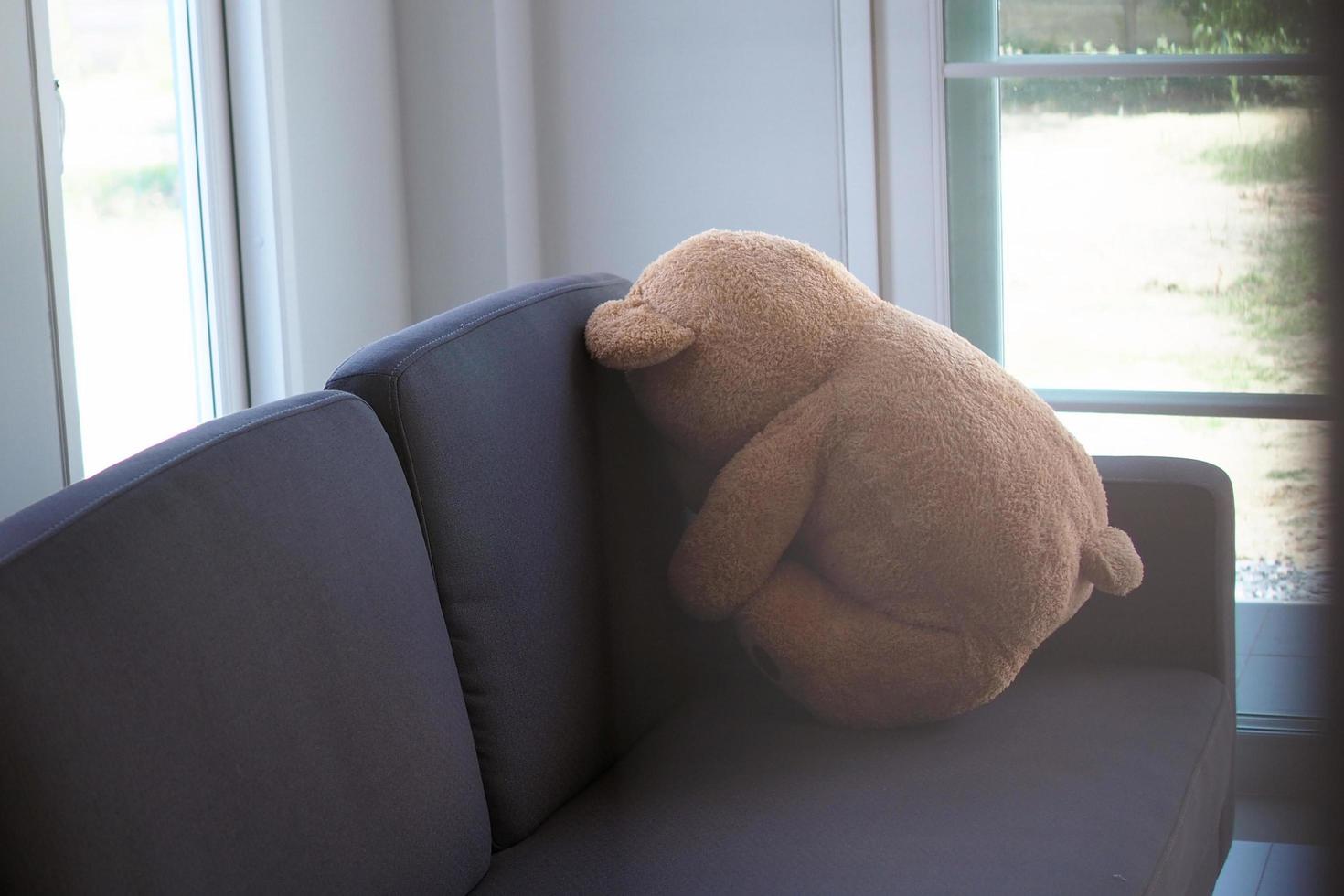 le concept de deuil des enfants. l'ours en peluche est assis sur le canapé à l'intérieur de la maison, seul l'air triste et déçu. photo