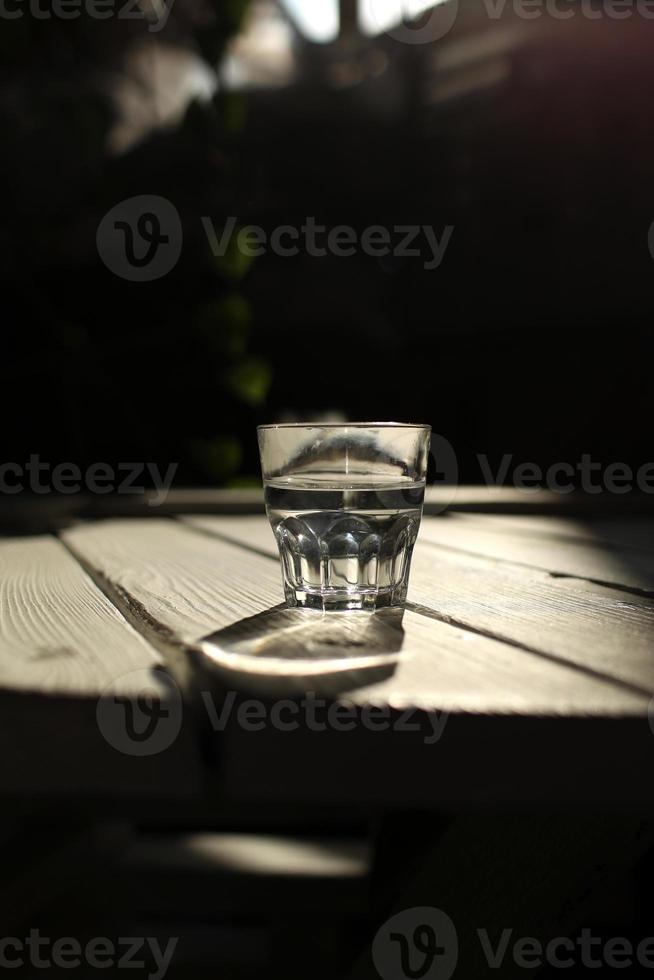 de l'eau claire dans un verre clair par contre. une alimentation saine et une eau naturelle respectueuse de l'environnement. un verre d'eau sur une table en bois. photo