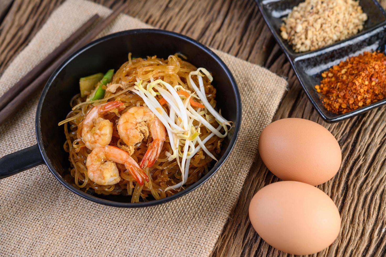 Pad thai crevettes dans une poêle noire avec des œufs et assaisonnement photo