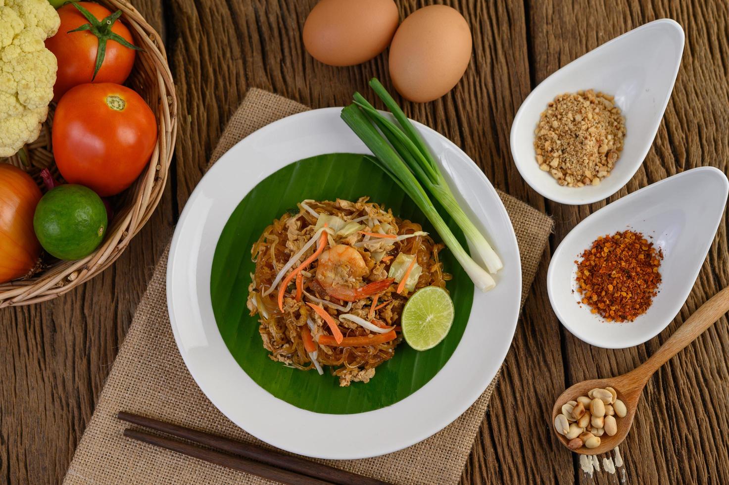 Pad thai crevettes dans un bol avec œufs, oignon nouveau et assaisonnements photo