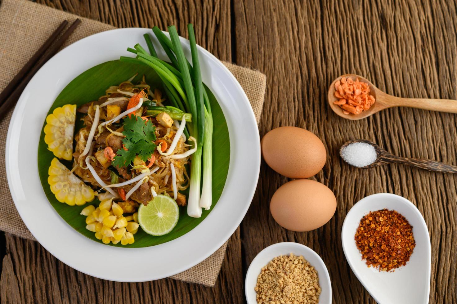 Pad thaï au citron, oeufs et assaisonnement sur une table en bois photo