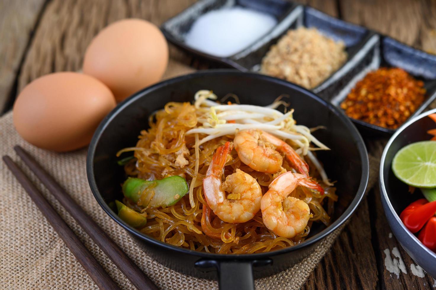 Pad thai crevettes dans une poêle noire avec des œufs et assaisonnement photo