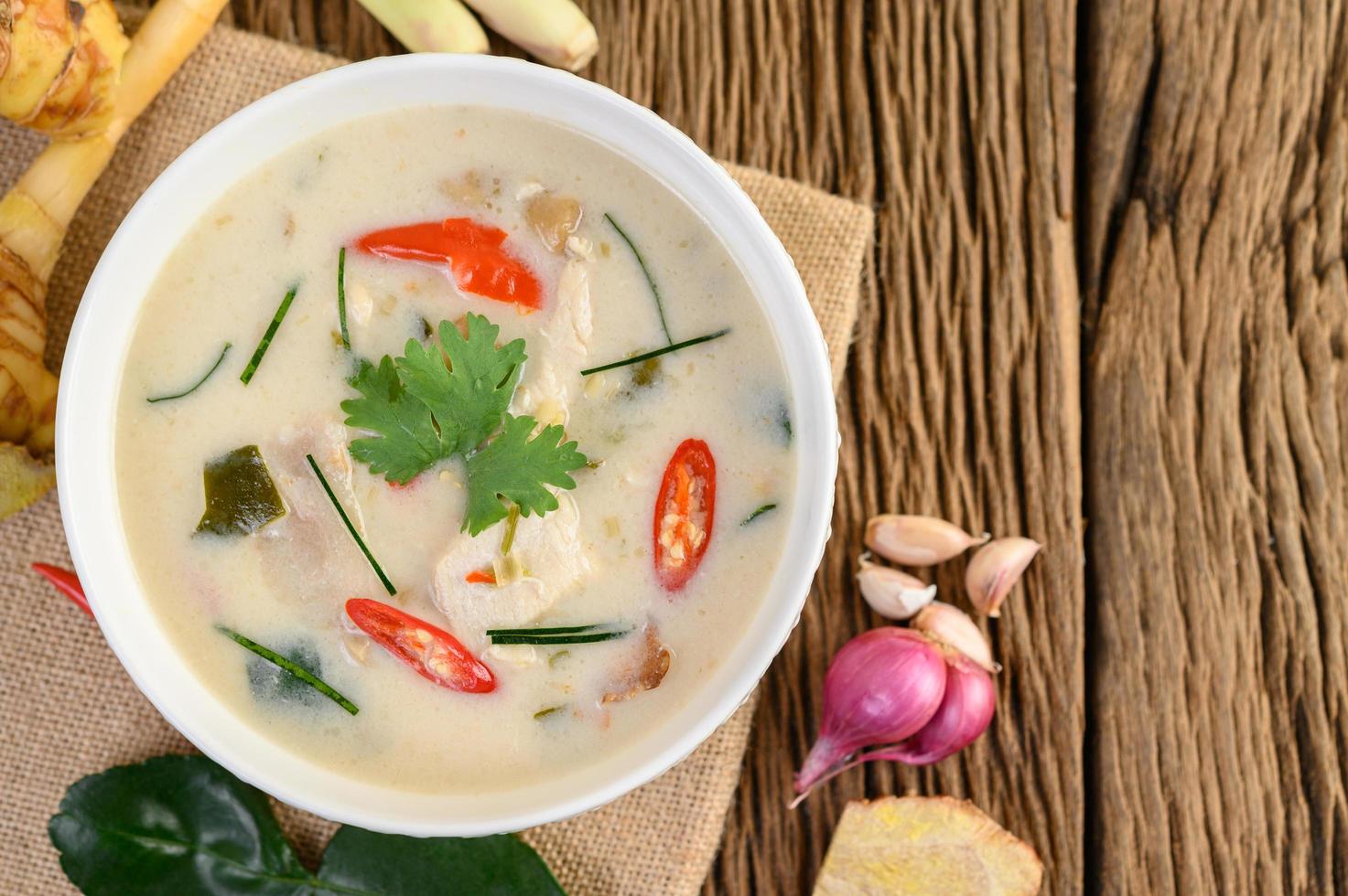 Tom kha kai, soupe de noix de coco thaï sur planche de cuisine en bois photo