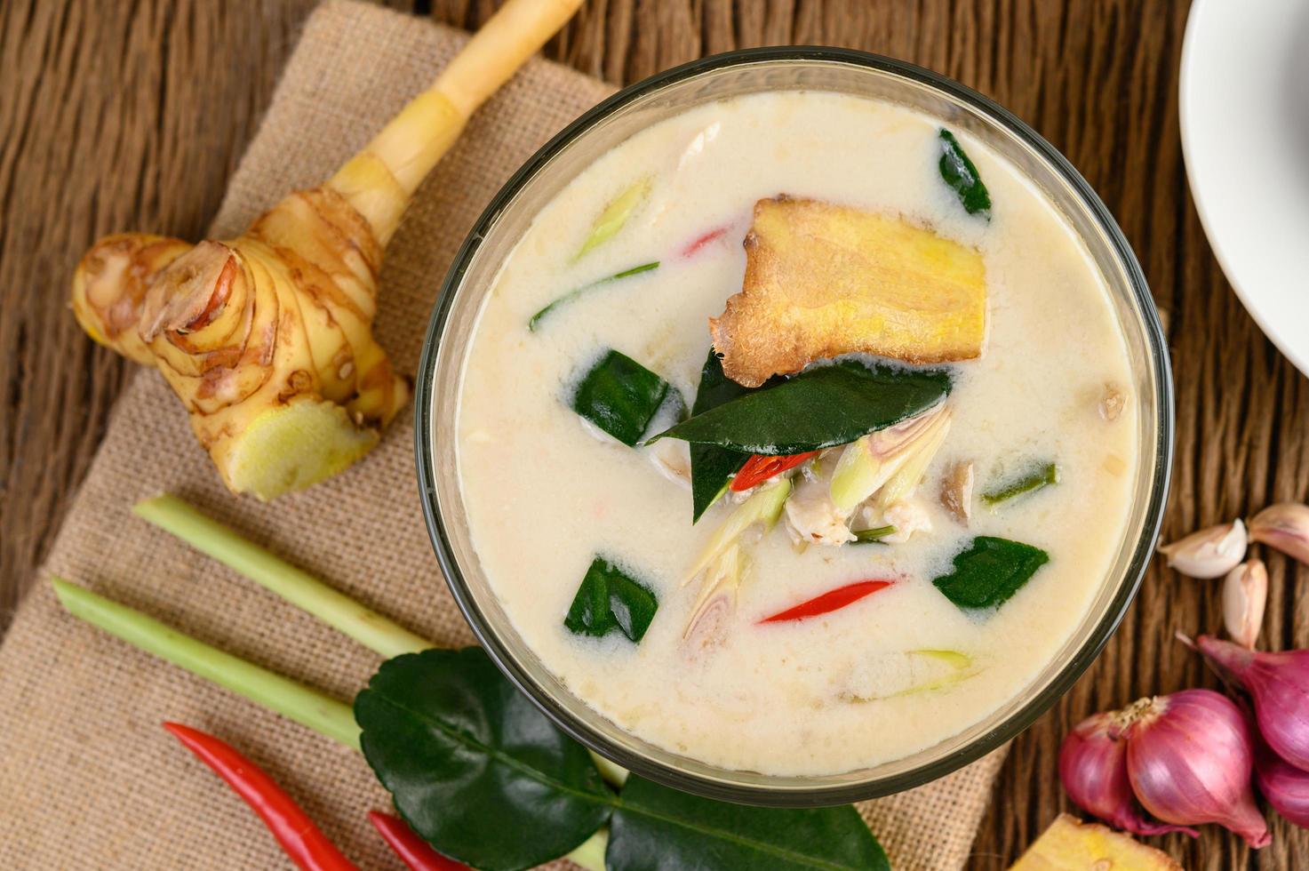 Tom kha kai, soupe de noix de coco thaï sur planche de cuisine en bois photo