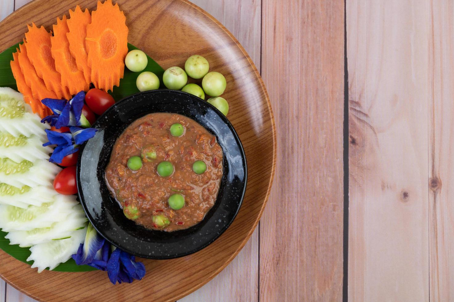 pâte de pâte de piment dans un bol avec aubergines, carottes, chili et concombres dans un panier photo