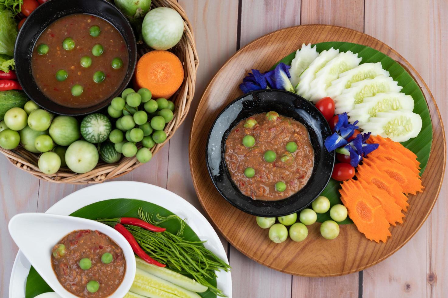 pâte de pâte de piment dans un bol avec aubergines, carottes, chili et concombres dans un panier photo