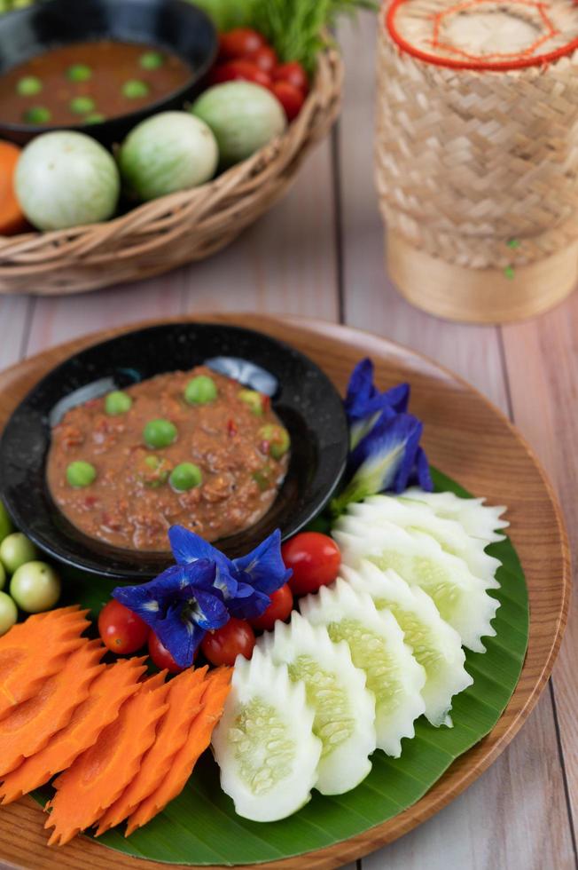 pâte de pâte de piment dans un bol avec aubergines, carottes, chili et concombres dans un panier photo