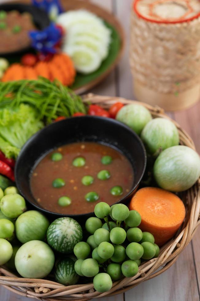 pâte de pâte de piment dans un bol avec aubergines, carottes, chili et concombres dans un panier photo