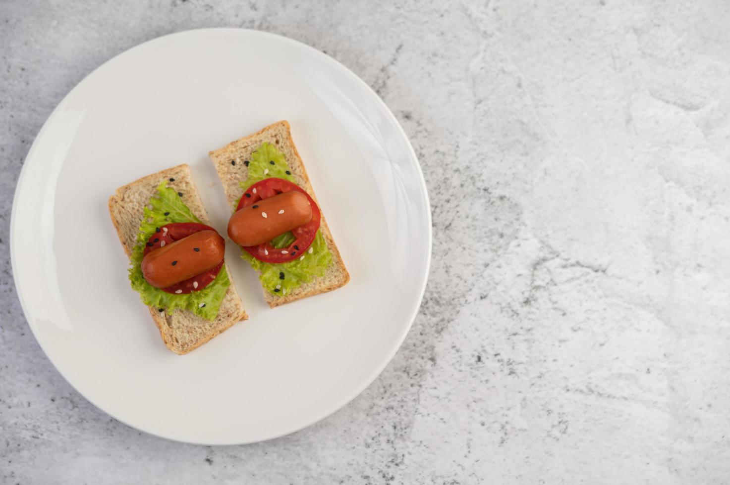 saucisse aux tomates et salade sur pain photo