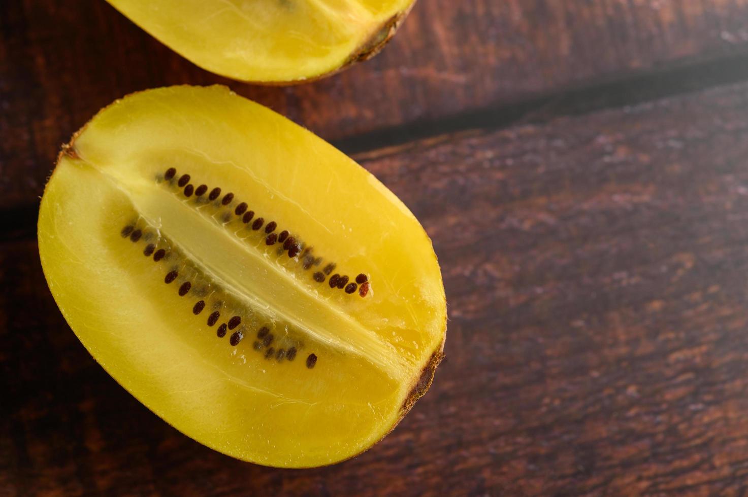 Un kiwi jaune à moitié coupé sur une table en bois photo