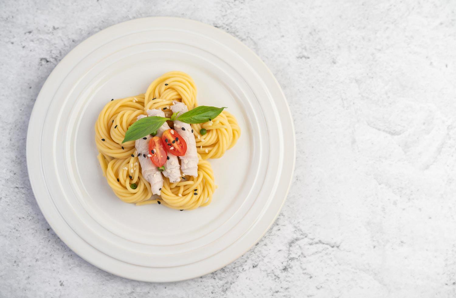 spaghetti et porc plaqués disposés sur une assiette blanche photo