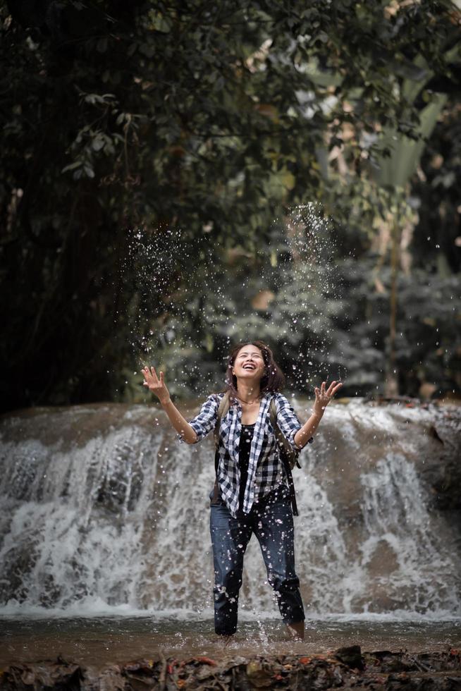 jeune femme s'amusant sous une cascade dans la forêt photo