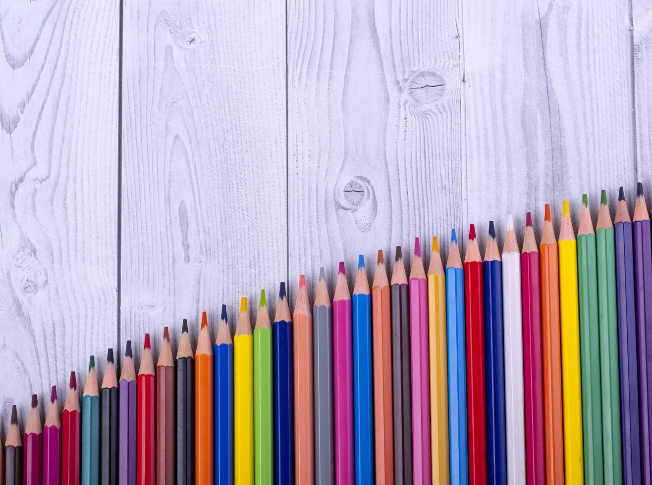 crayons de couleur en bois, disposés en forme d'échelle, sur fond gris et blanc. concept de l'éducation. photo