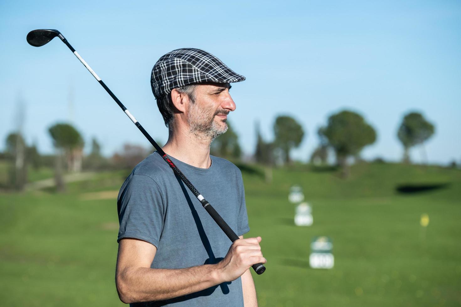 joueur de golf avec casquette et club sur son épaule sur un parcours de conduite photo