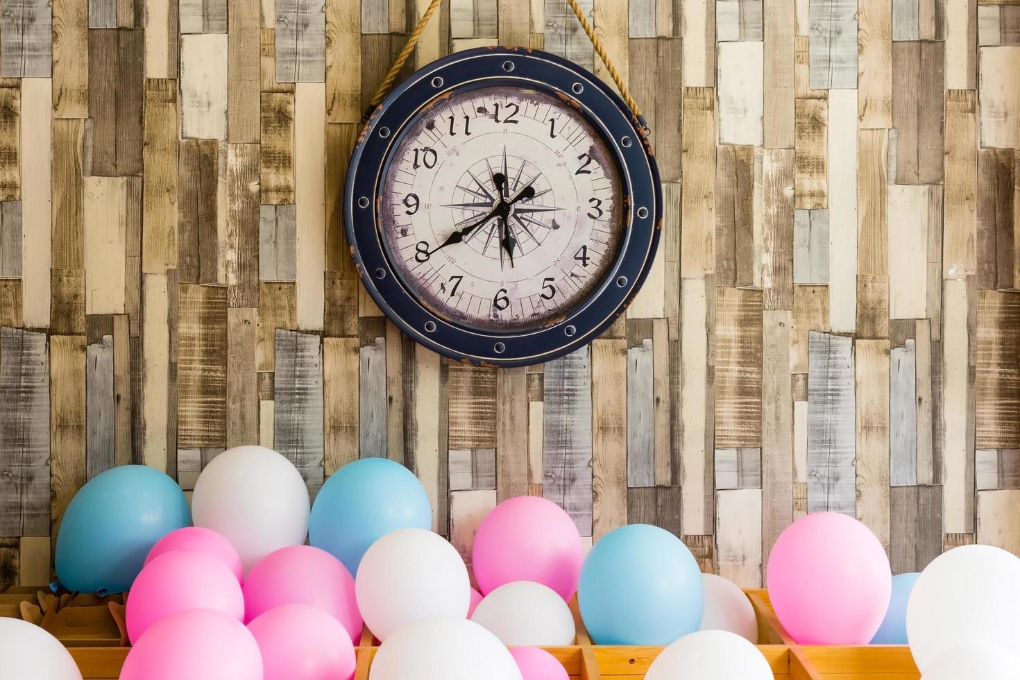 horloge vintage accroché sur le fond de mur en bois avec des ballons colorés photo