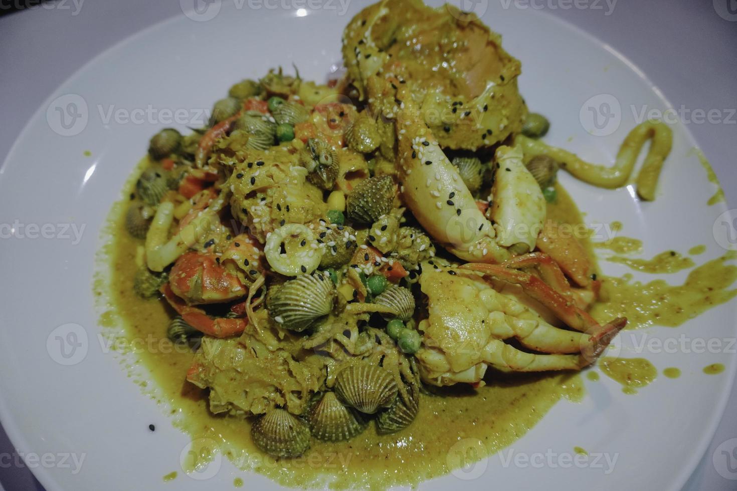 une photo d'une assiette de fruits de mer contient des crabes, des crevettes, des calmars et des palourdes