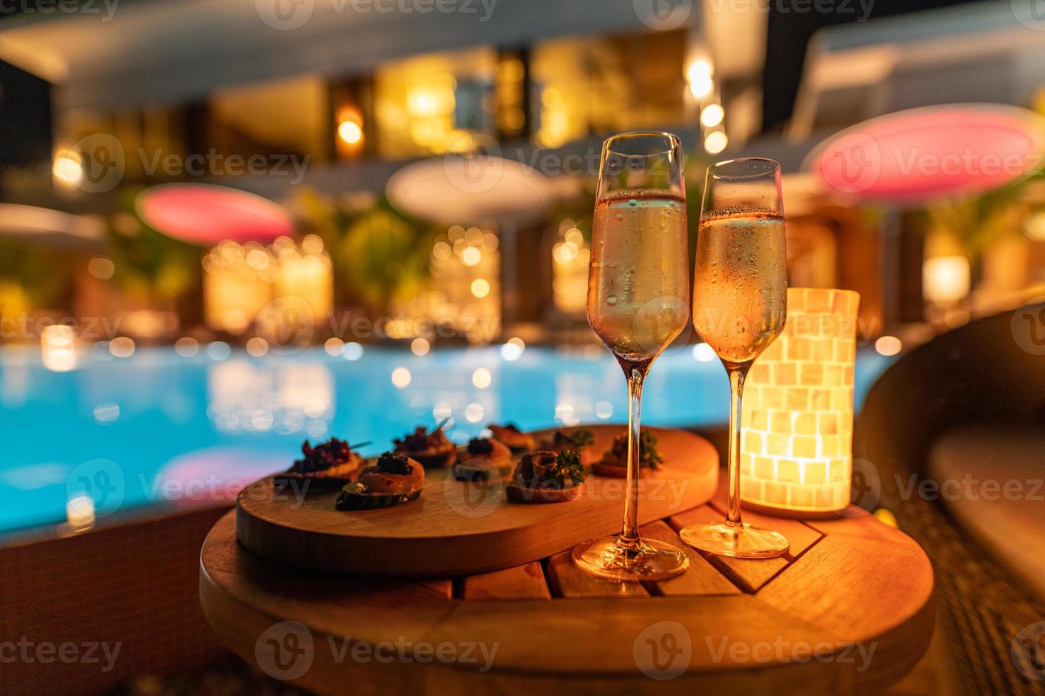 décoration romantique table à dîner aux chandelles pour la fête avec des plats spéciaux au champagne et lumière floue de la piscine et de la maison. fête de luxe ou événement de vacances photo