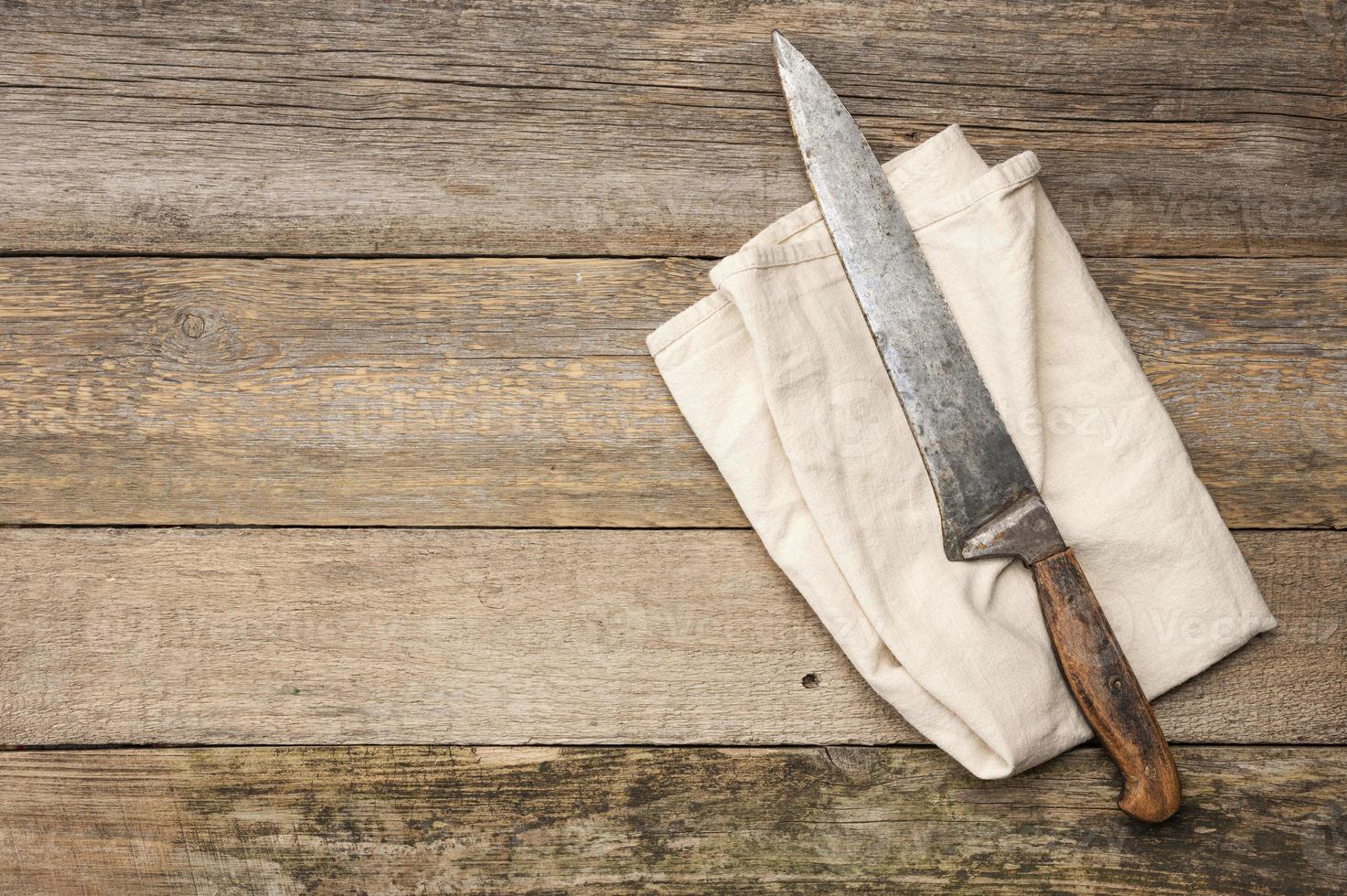 très vieux couteau et torchon de cuisine en lin gris sur une table faite de vieilles planches de bois photo