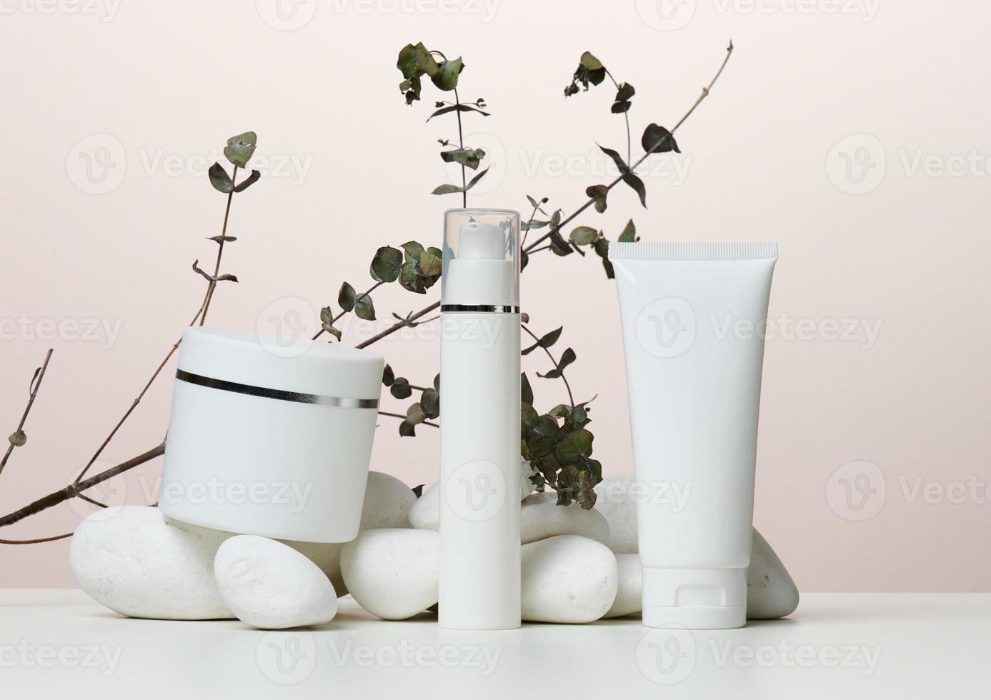 pot, bouteille et tubes en plastique blanc vides pour cosmétiques sur fond beige. photo