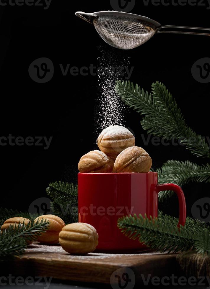 dessert cuit au four en forme de noix dans une tasse en céramique rouge. du sucre en poudre est versé dessus photo