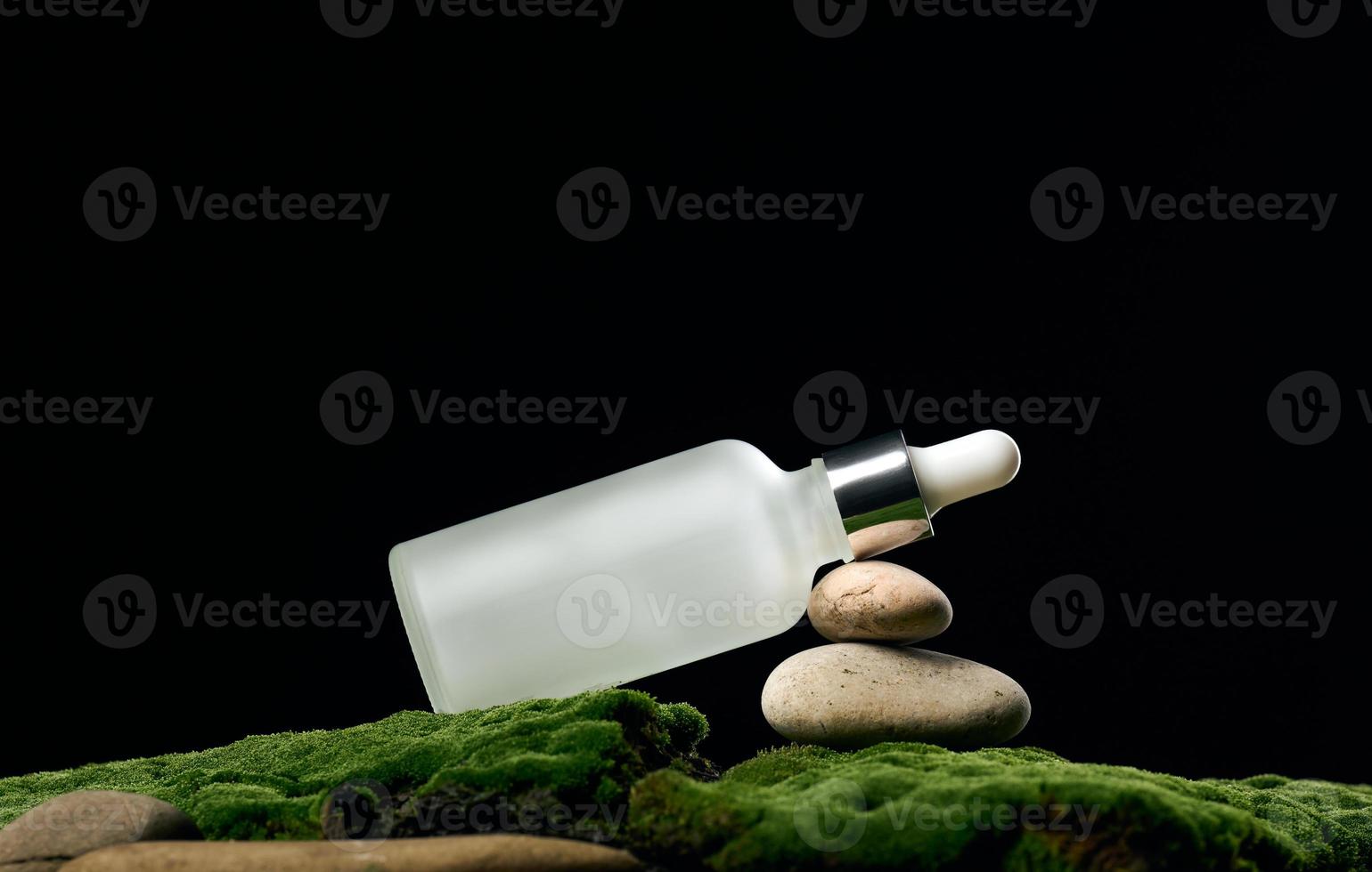 bouteille en verre blanc avec pipette se dresse sur mousse verte, fond noir. marque de spa cosmétique. emballage pour gel, sérum, publicité et promotion de produits, maquette photo