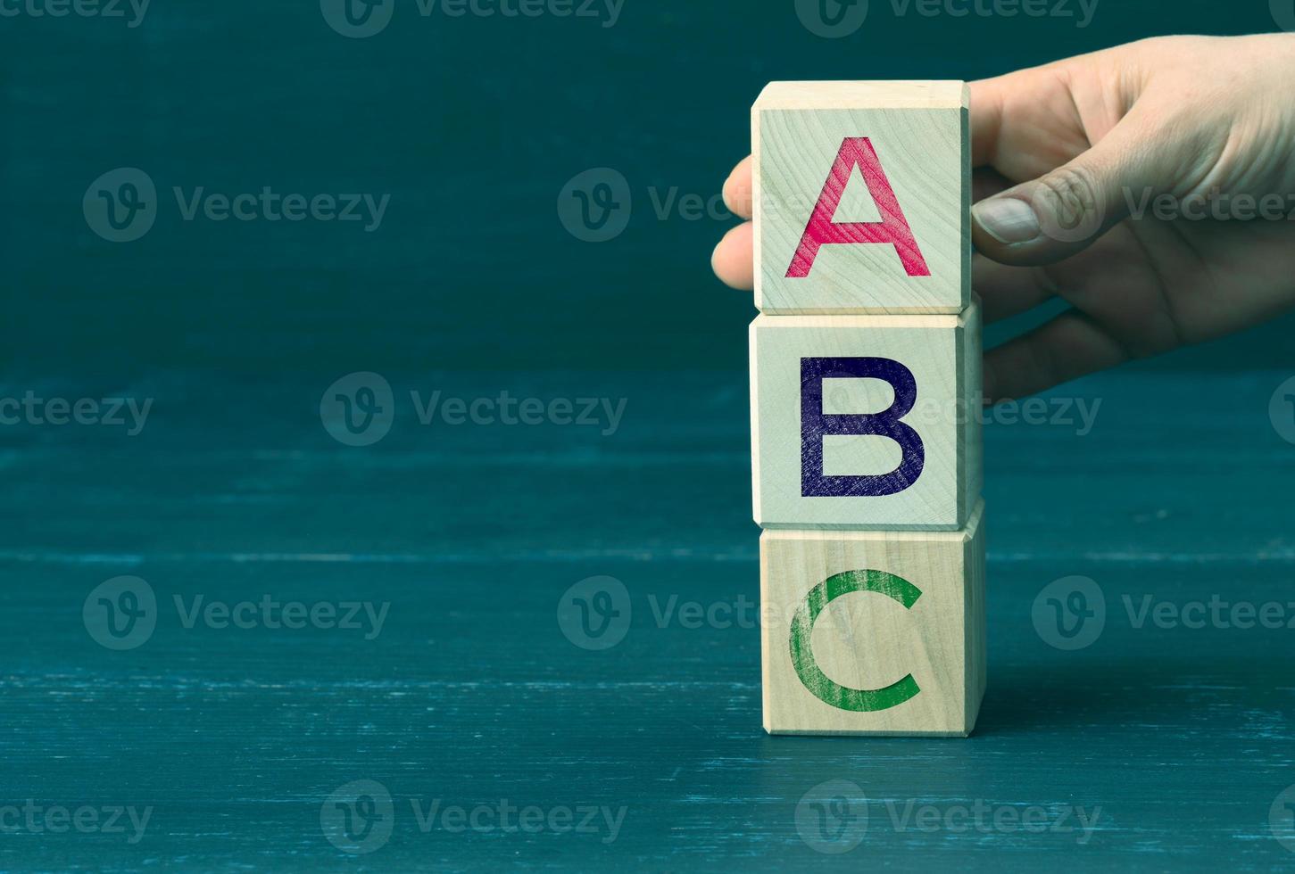 la main tient des cubes en bois avec des lettres a, b, c. concept d'éducation préscolaire. des vérités simples et une liste de réalisations et d'objectifs photo