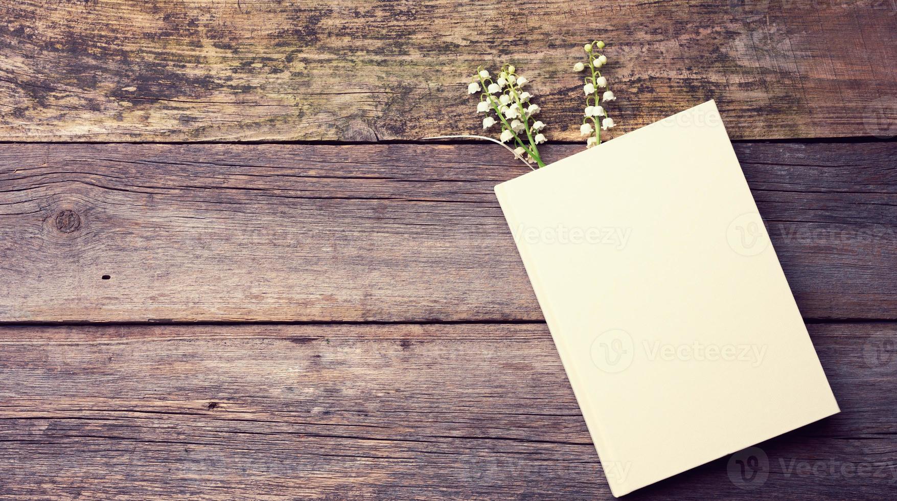 cahier avec des feuilles blanches vierges et un bouquet de lis de la vallée en fleurs sur une table en bois à partir de planches grises photo