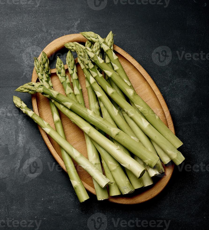 bouquet d'asperges crues fraîches sur une planche de cuisine noire en bois, un produit sain photo