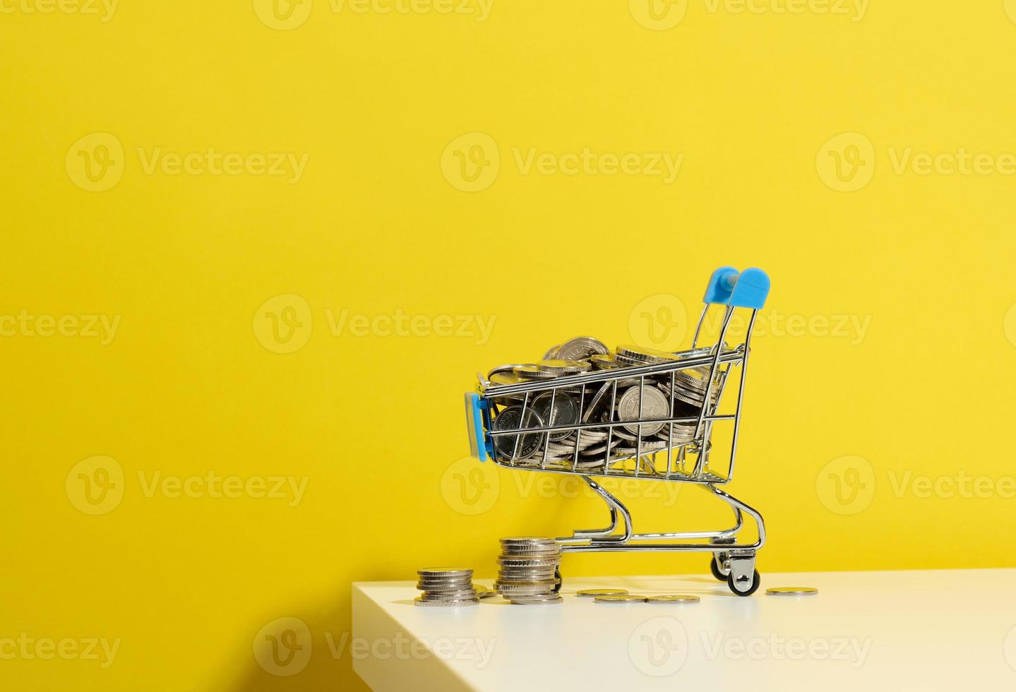 panier miniature en métal et une pile de pièces sur un tableau blanc. le concept de remises et de ventes, les économies budgétaires. commerce en ligne photo