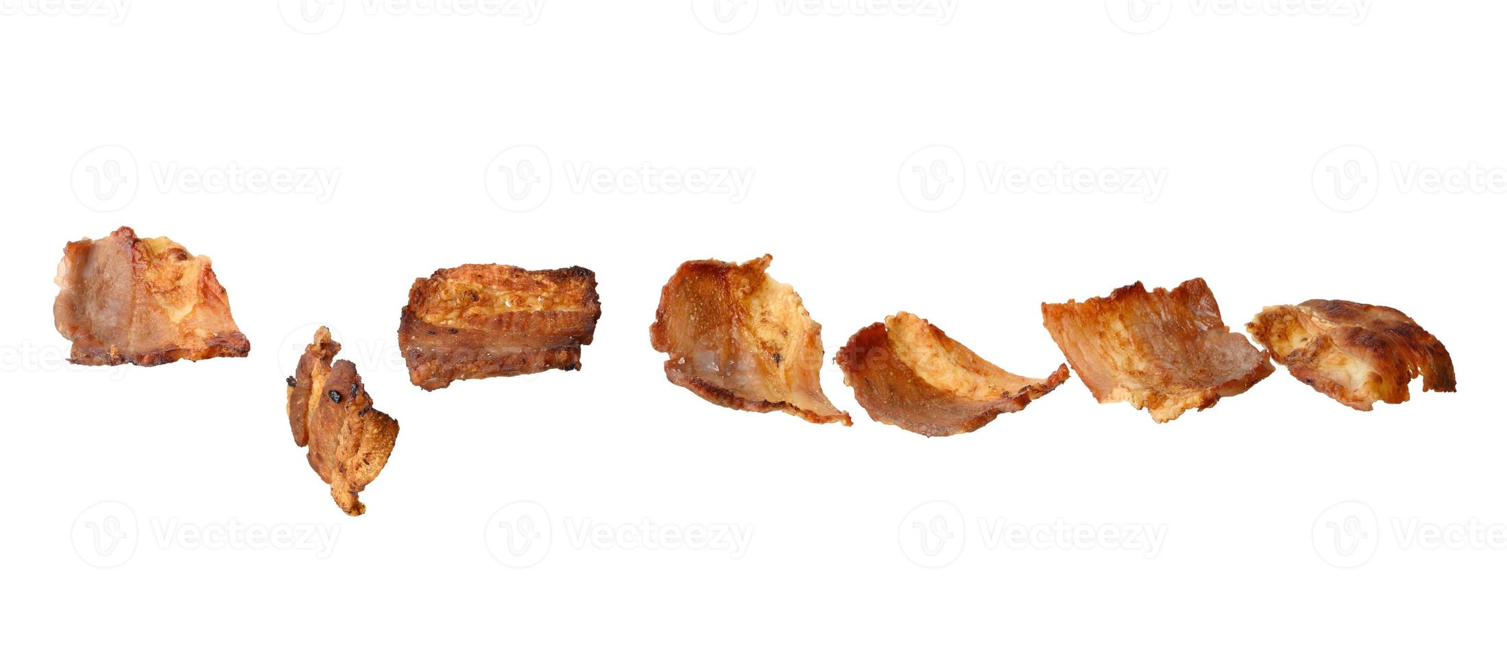 Divers petits morceaux de bacon frit isolés sur fond blanc photo